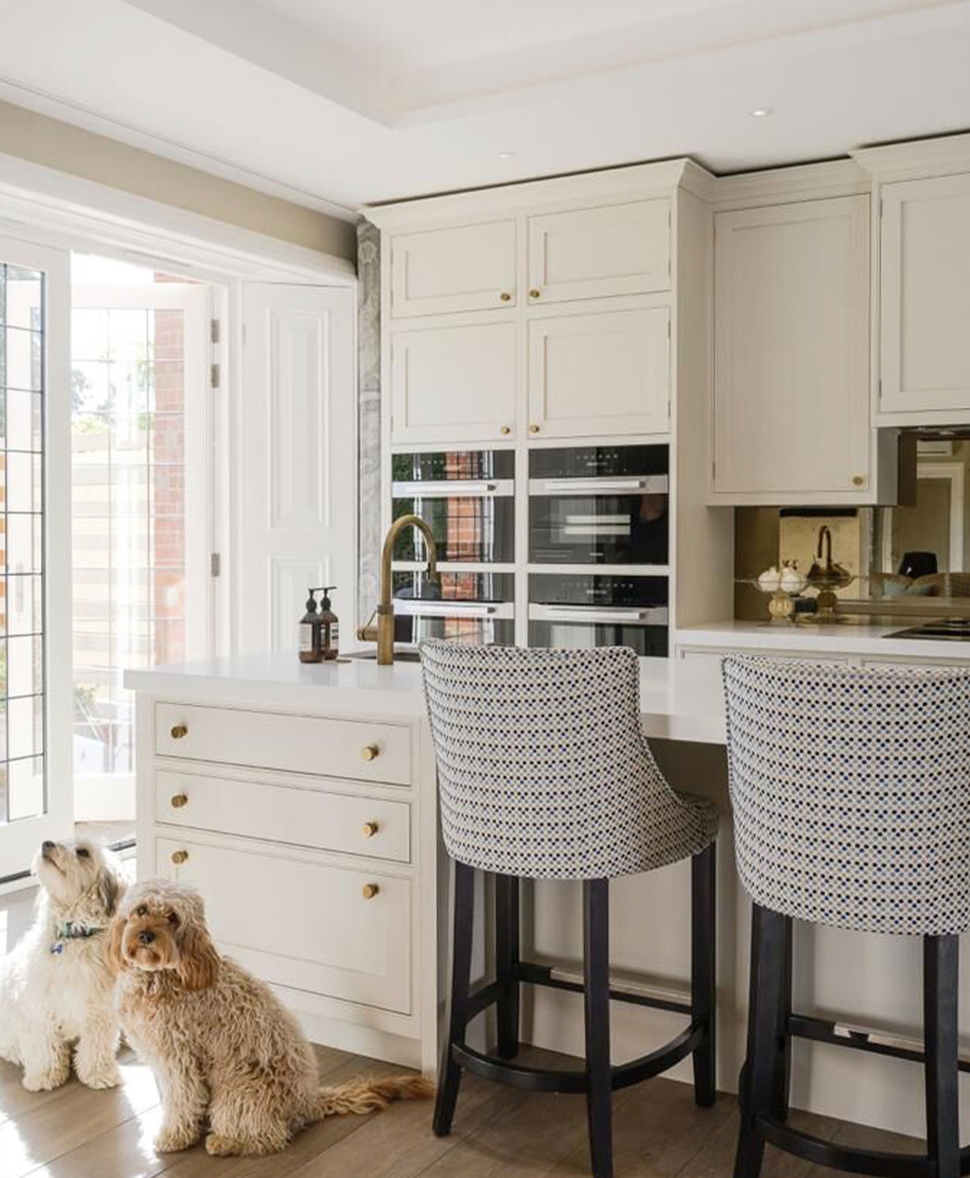 Modern kitchen with white cabinets, a dog sitting on the floor, and two bar stools.