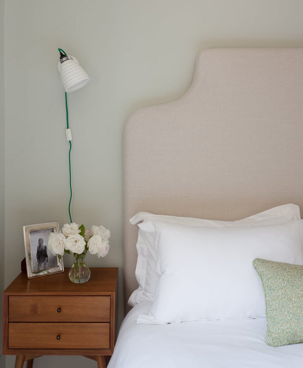 mint green Bedroom with a bed, nightstand, and wall lamp.