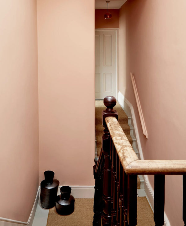 Staircase with wooden banister and pink walls