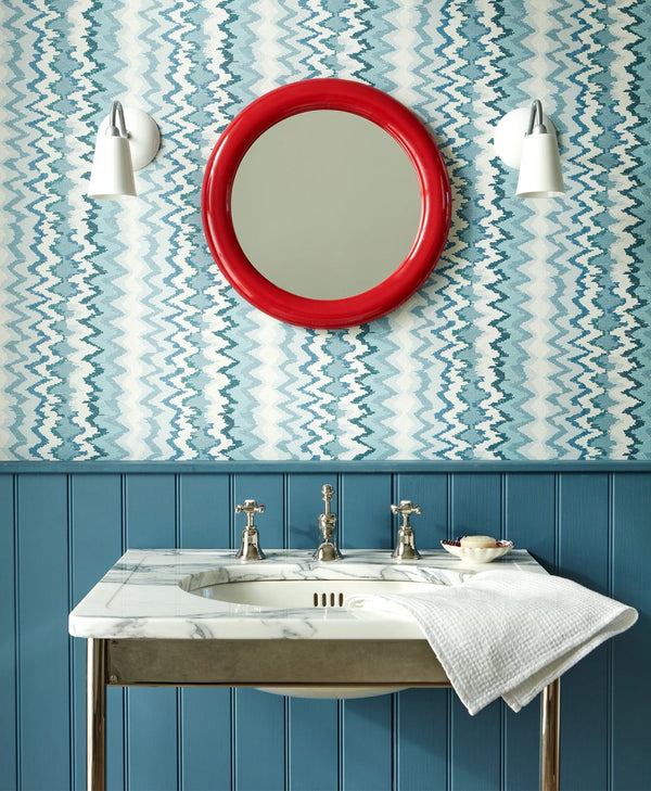 marine blue Bathroom with a red round mirror, sink, and decorative wall pattern.