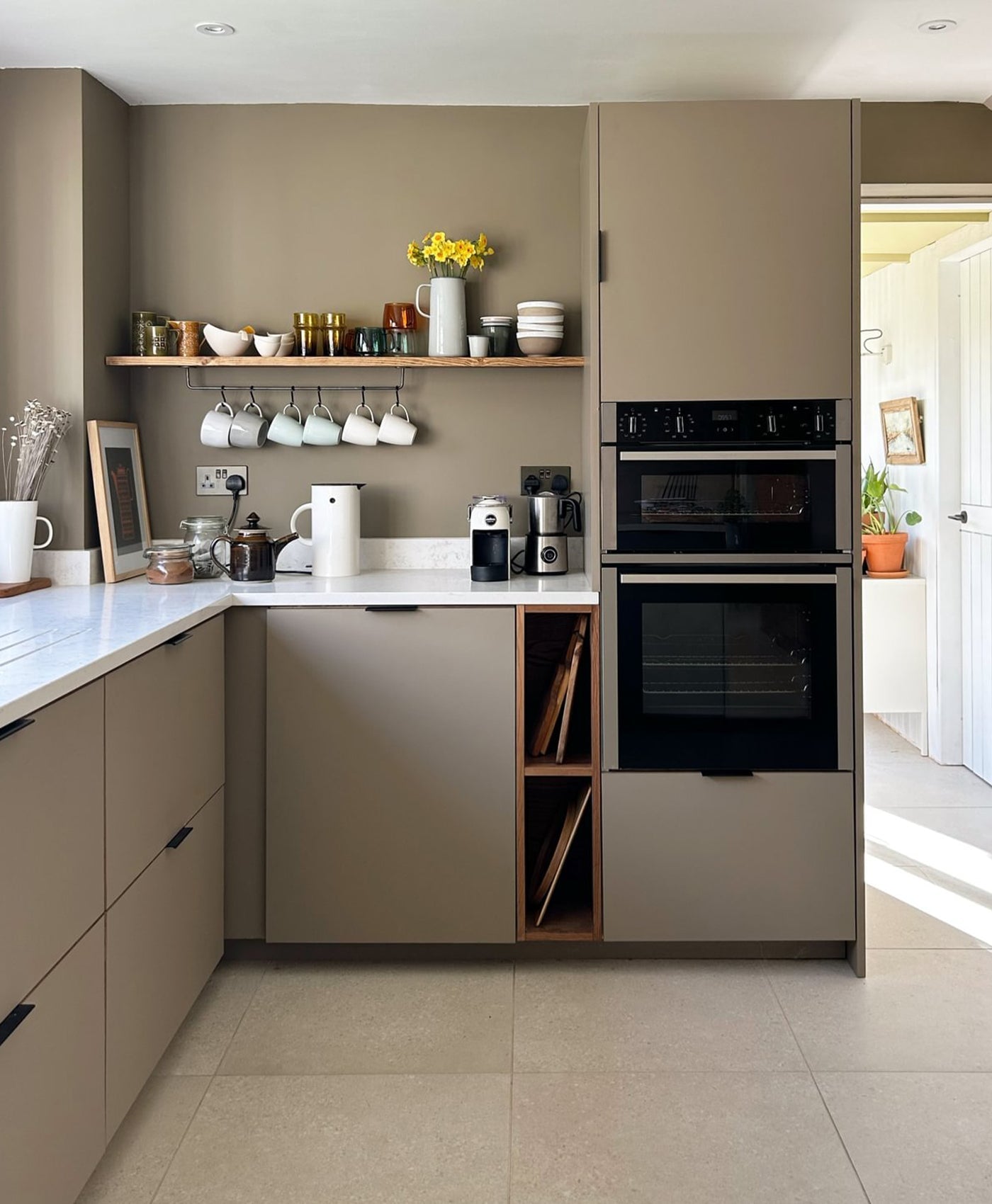 Modern kitchen with clay coloured cabinets, black appliances, and white countertops.