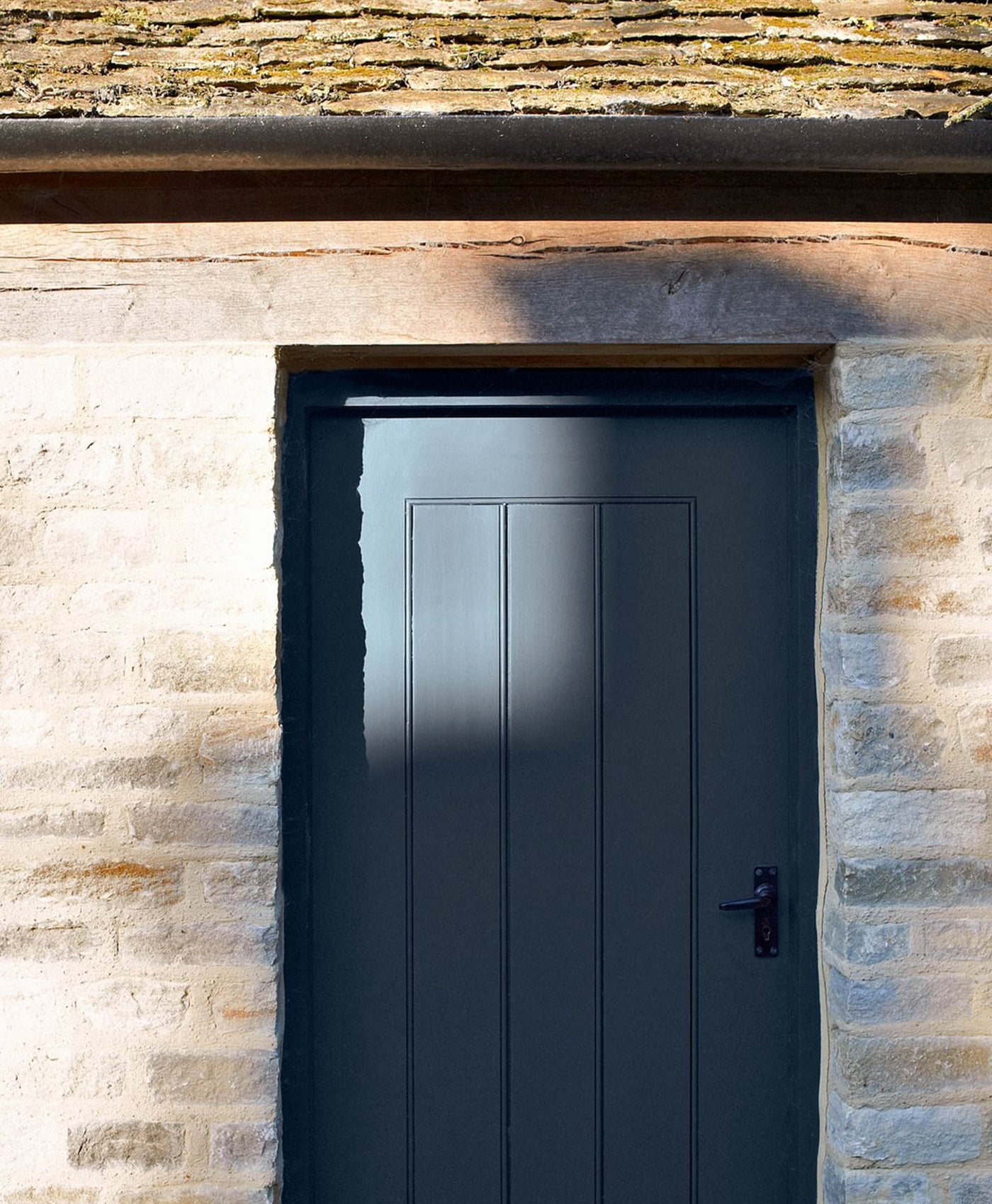 Dark blue-grey door set in a stone wall with a rustic roof.