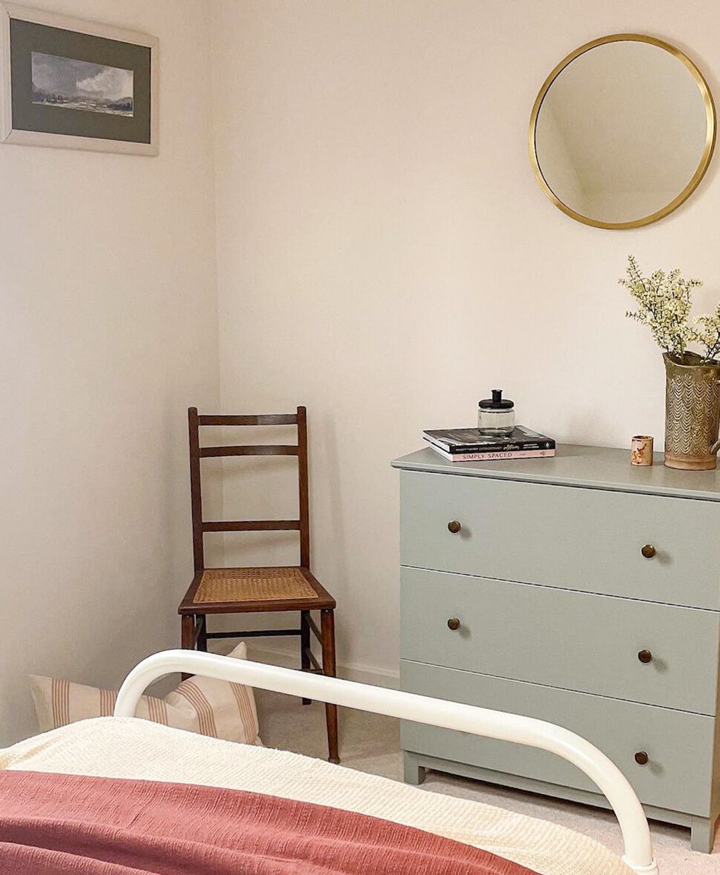 Soft white bedroom interior with a bed, wooden chair, and light green dresser.