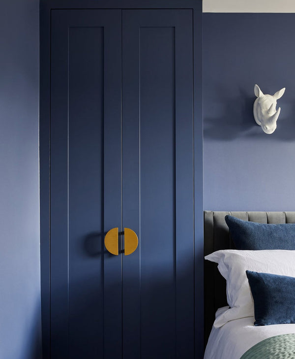 Navy blue wardrobe with gold handles in a bedroom setting