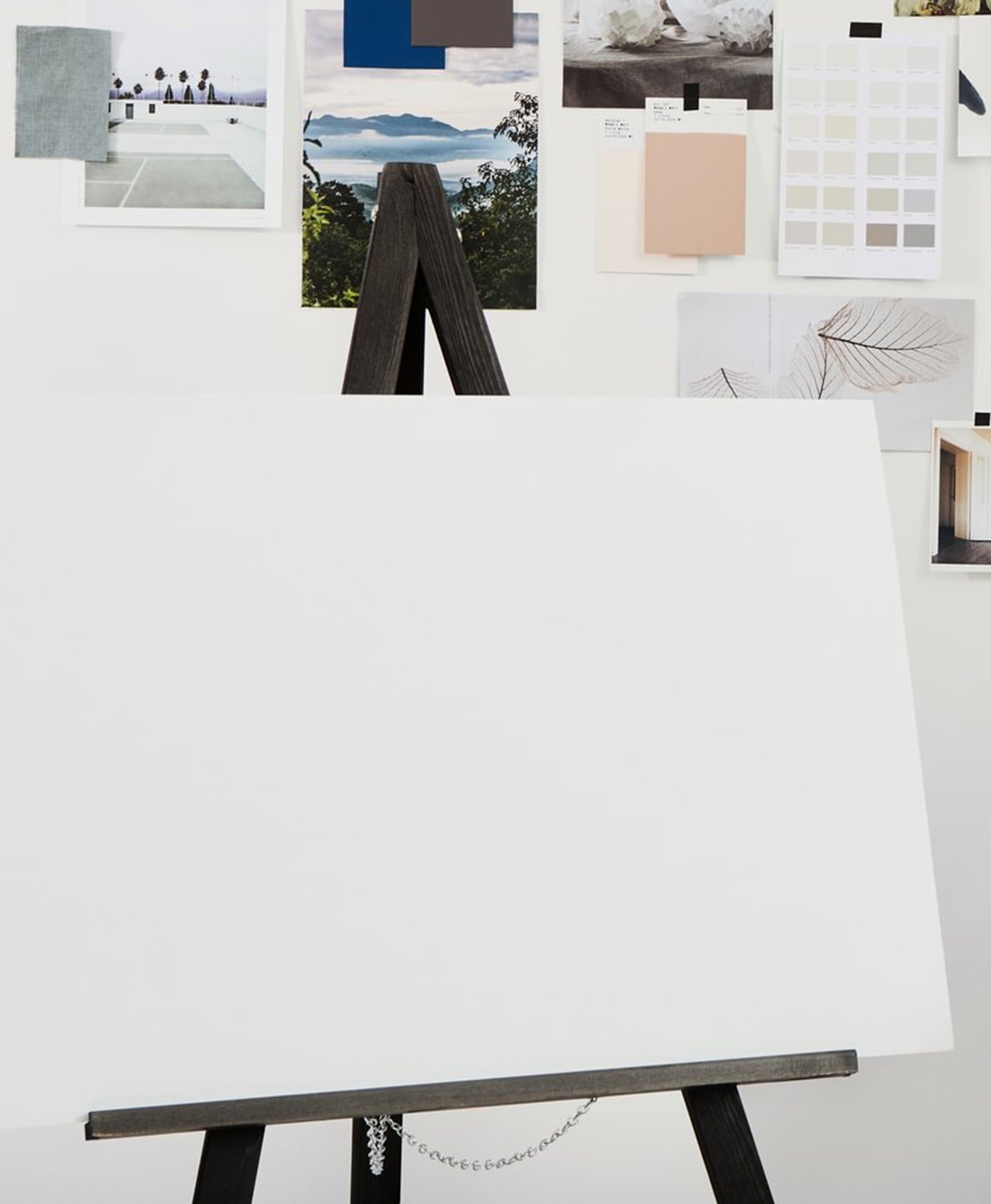 White canvas on an easel with a collage of images and color swatches in the background.