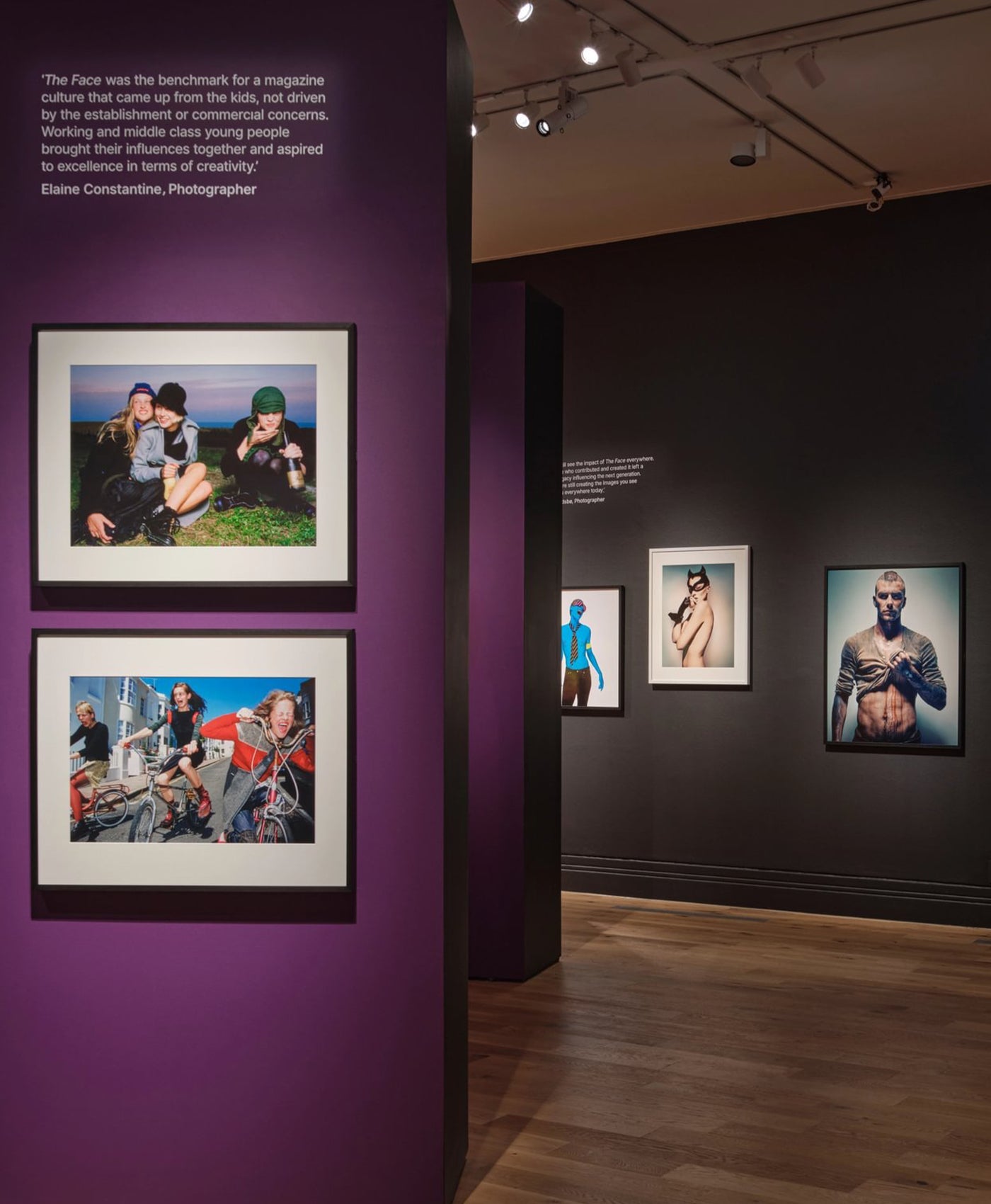 Art gallery exhibition with framed photographs on purple and black walls.