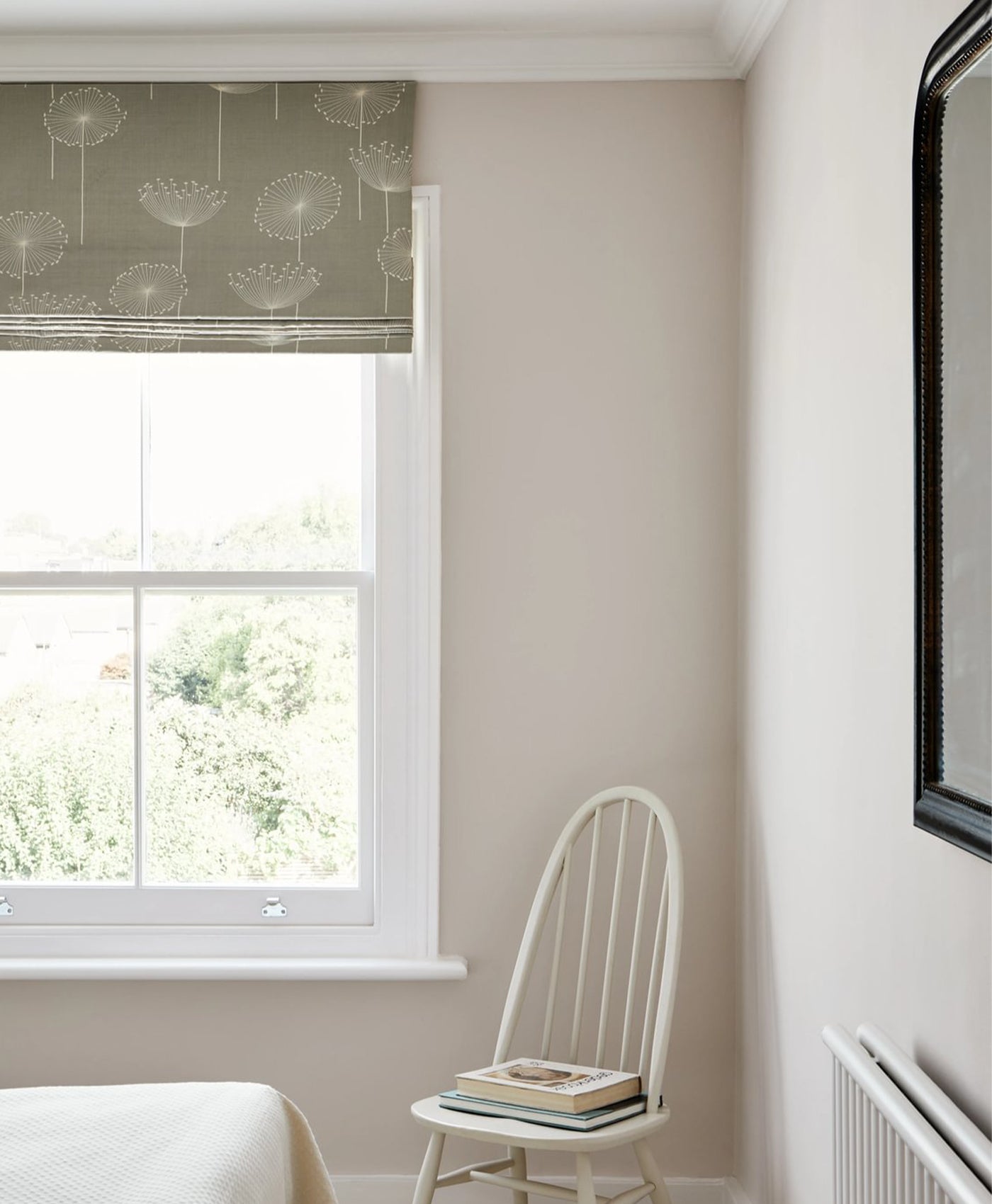 Small light neutral room with a window, chair, and mirror on a beige wall.
