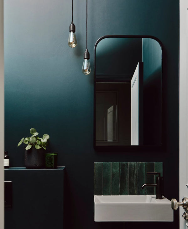 Modern bathroom interior with dark green wall, mirror, and sink.