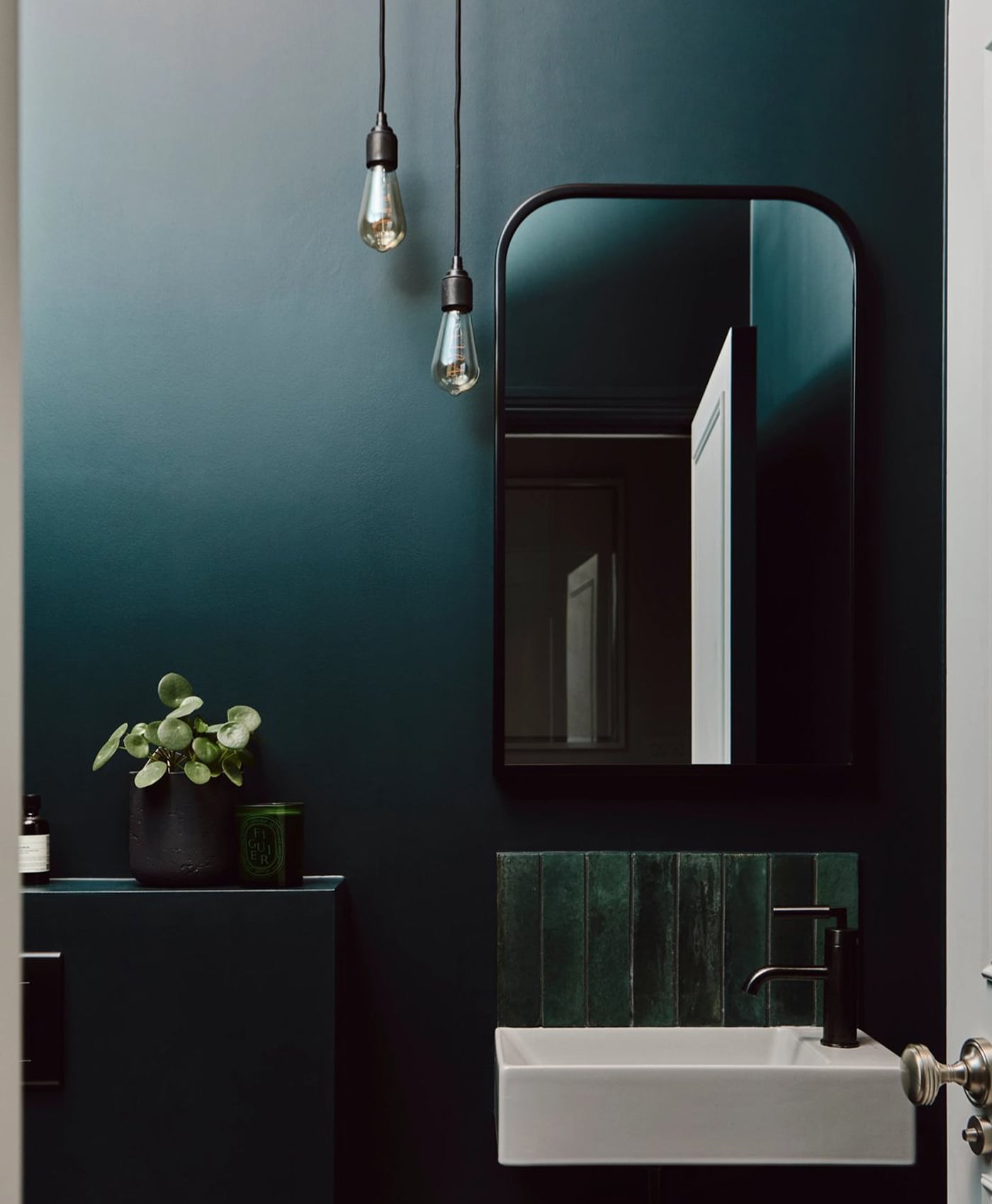 Modern bathroom interior with dark green wall, mirror, and sink.