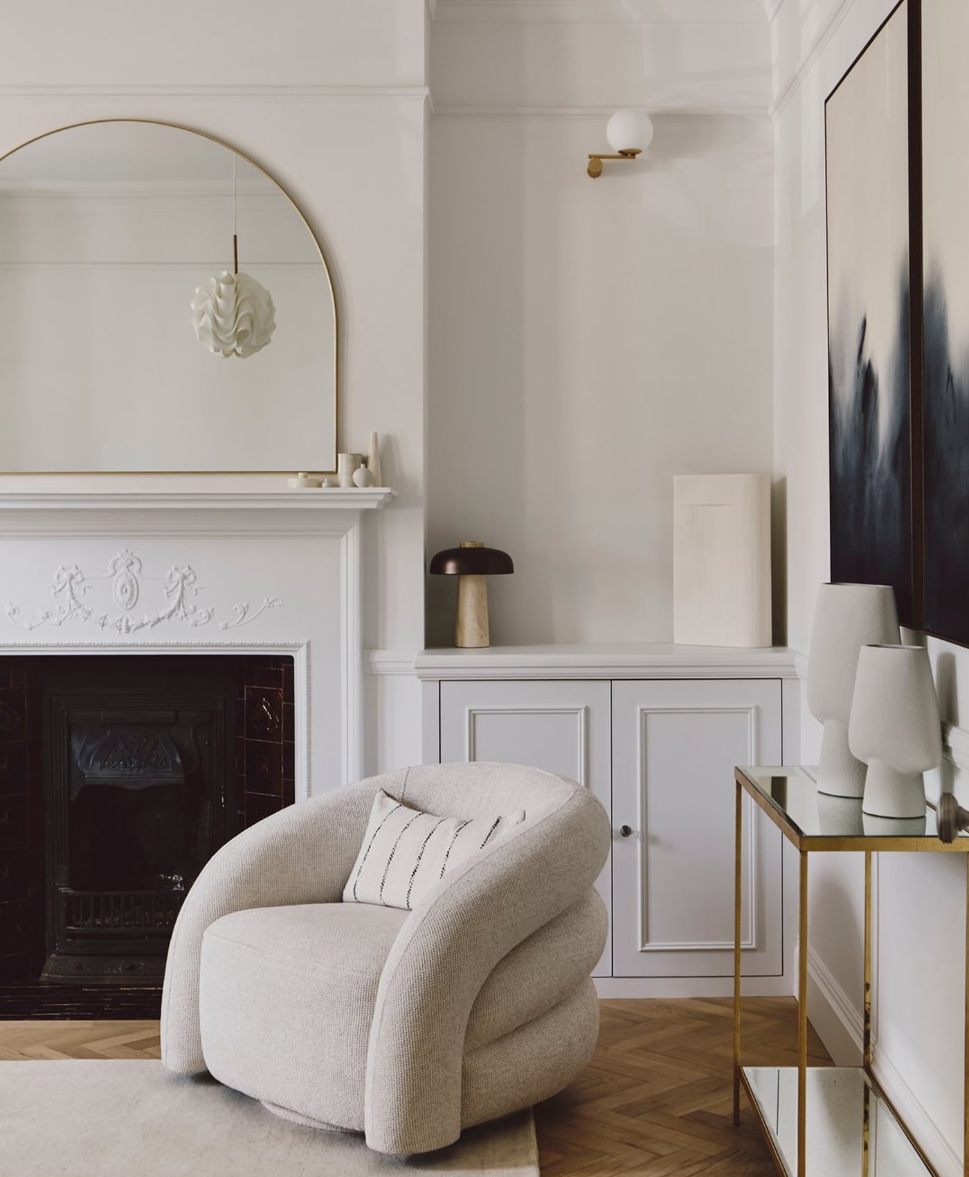 Coll white modern living room with a beige armchair, fireplace, and decorative items.