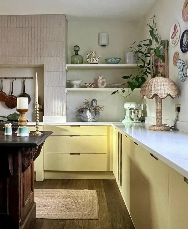 Modern kitchen with yellow cabinets, white countertops, and decorative items.