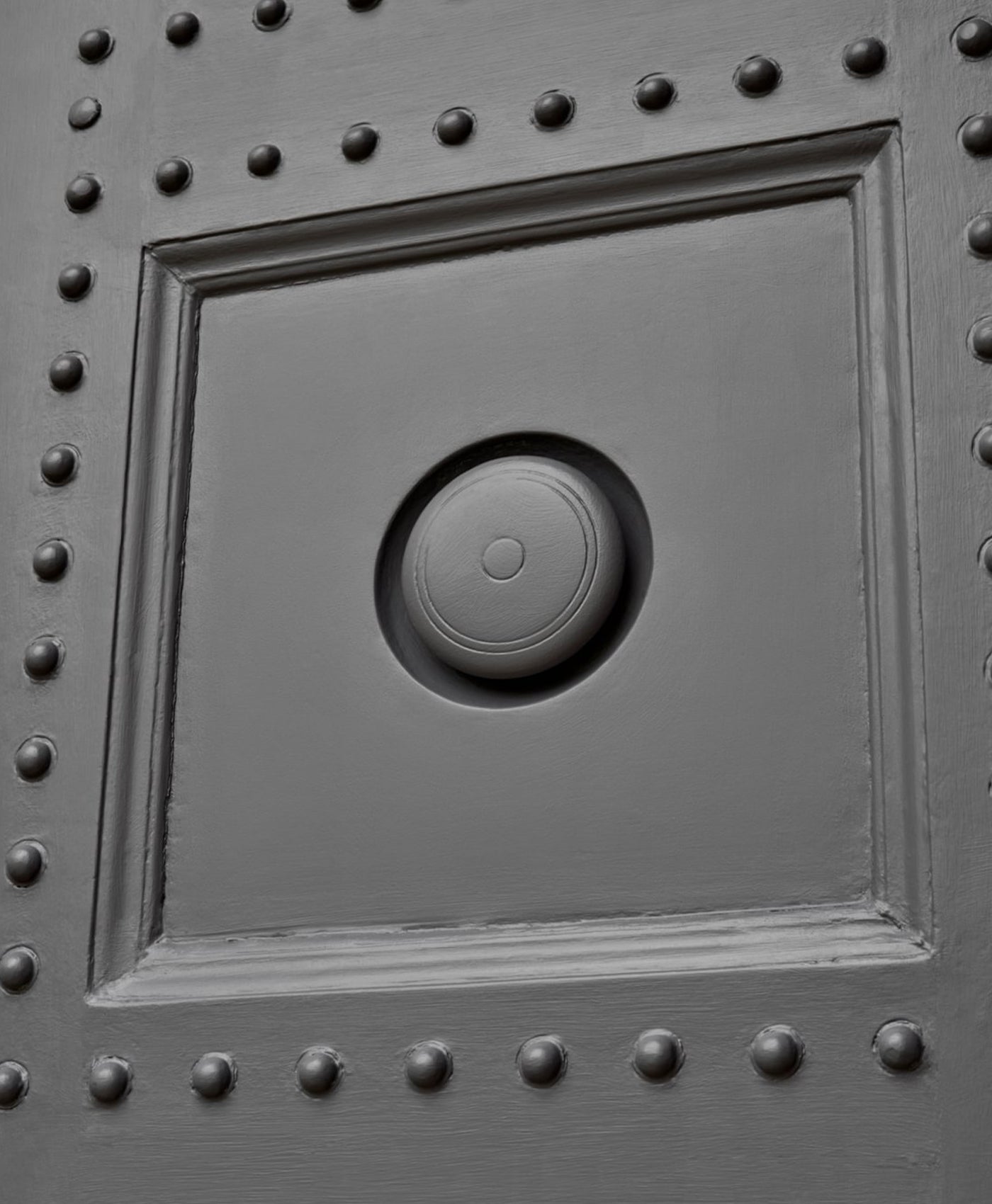 Decorative door panel with circular design and rivets painted in steel grey paint