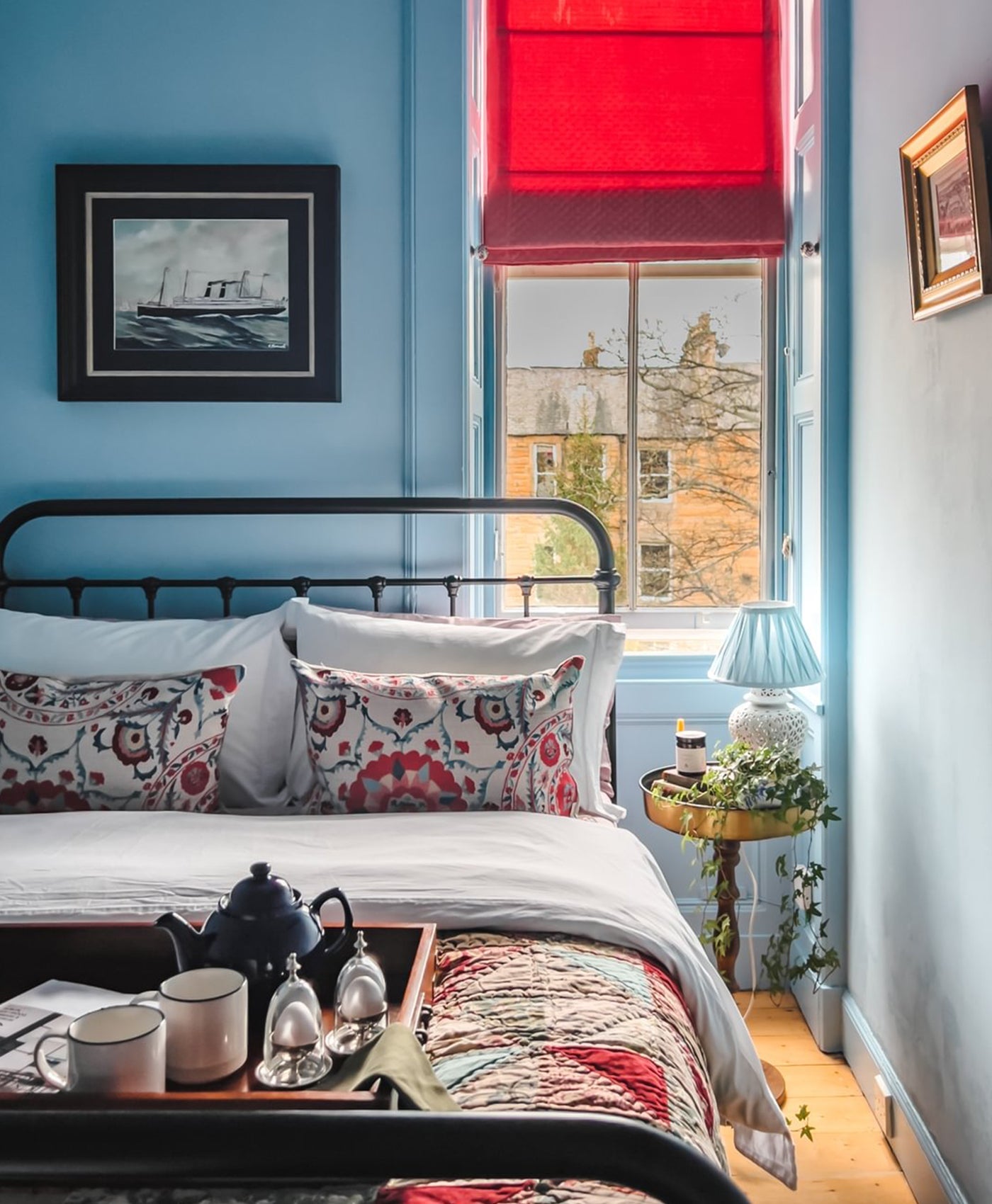 Cosy sky blue bedroom with a bed, tray with tea set, and decorative pillows.