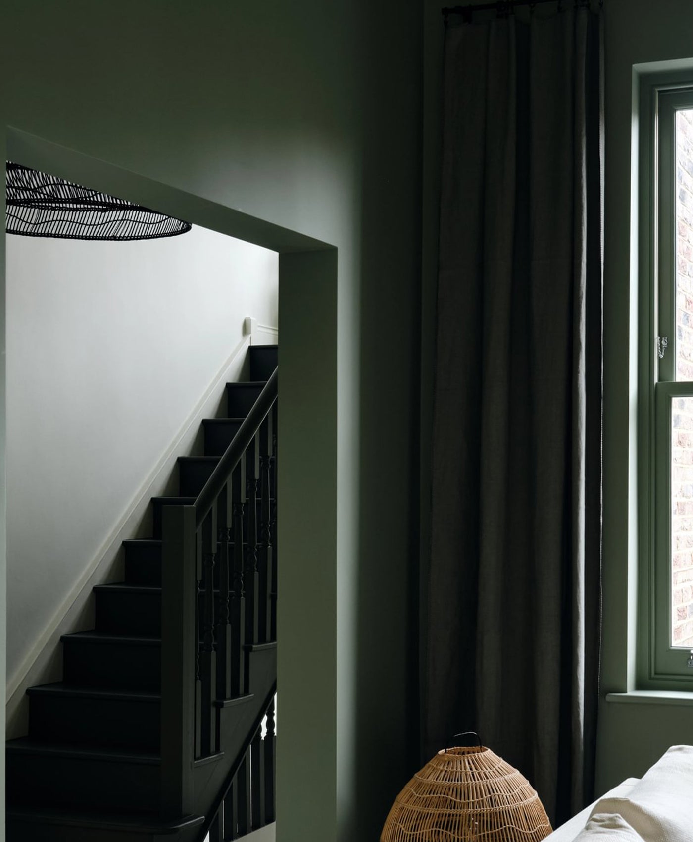 Dark green staircase in a olive green living room with a window and curtain