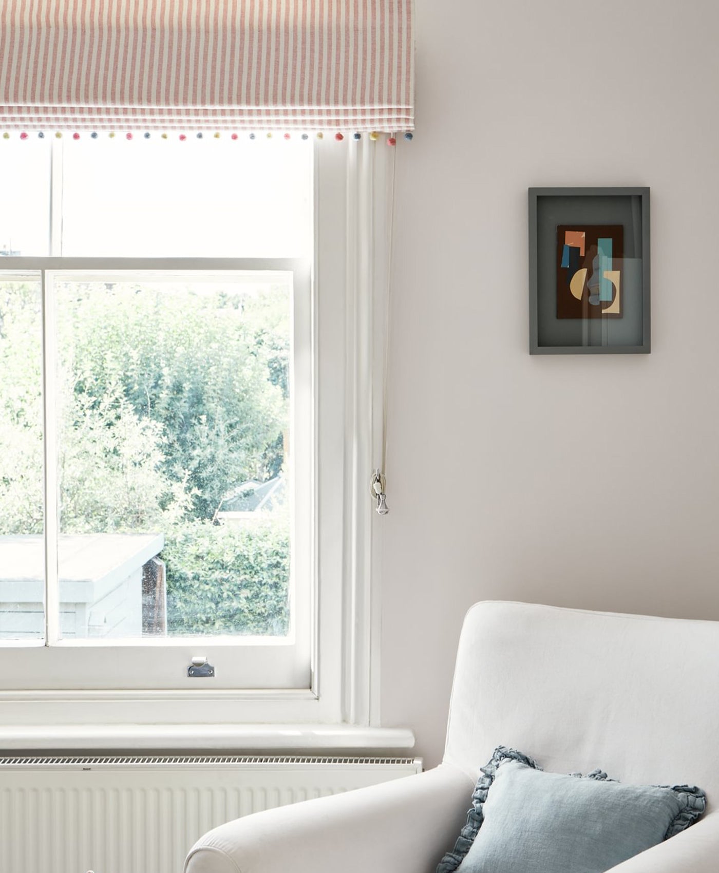Light neutral living room with a window, white sofa, and abstract painting on the wall.