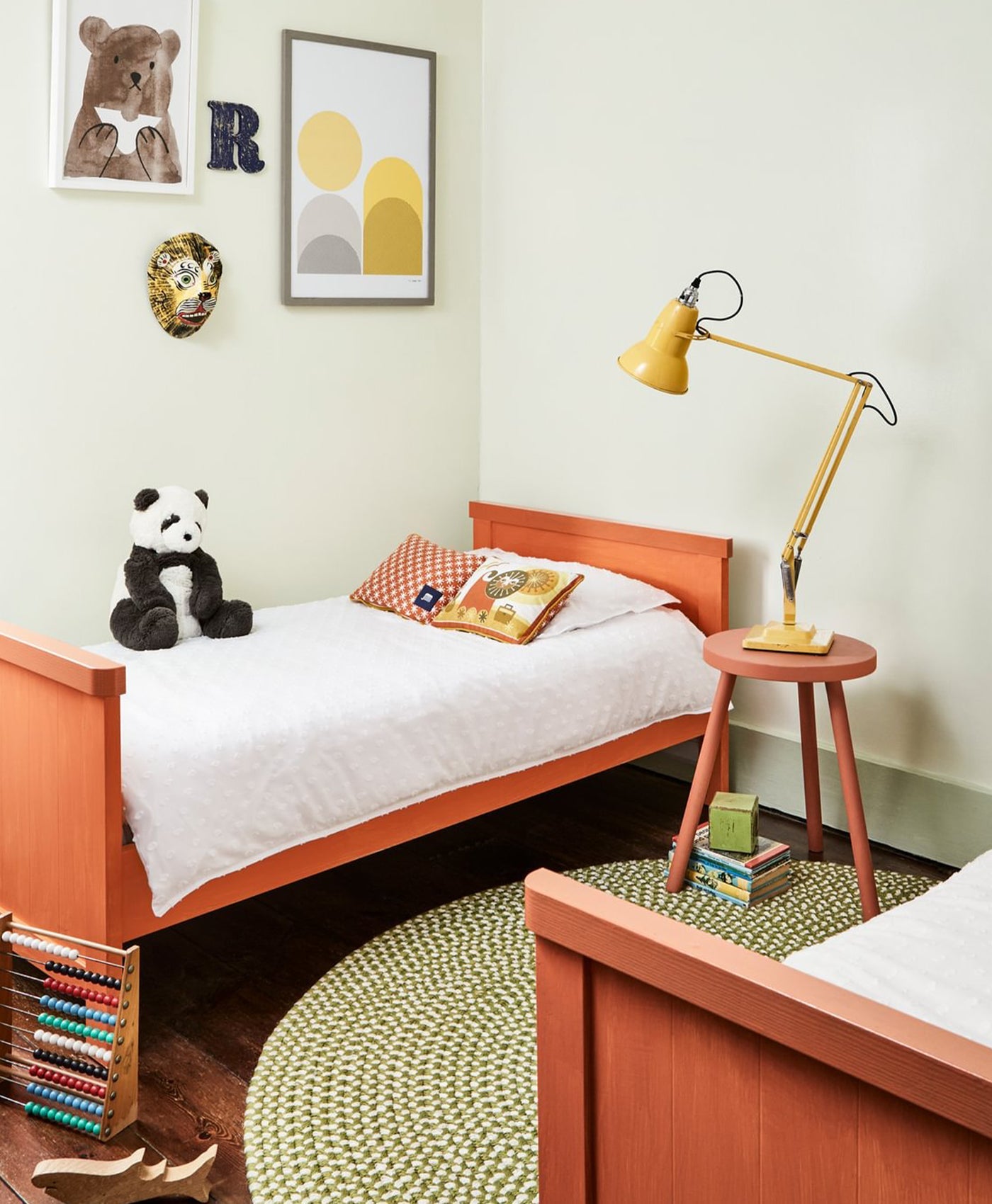 Children's bedroom with orange bed, pale yellow walls, panda toy, and lamp.