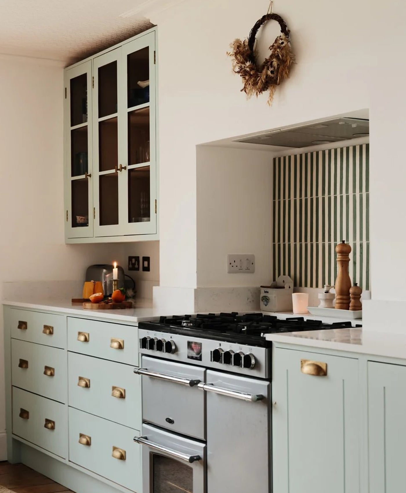 Kitchen with mint green cabinets, black stove, and decorative elements.