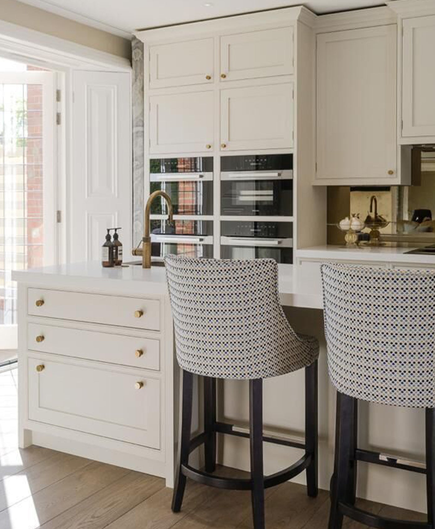 Modern kitchen with white cabinets, bar stools, and a window view.
