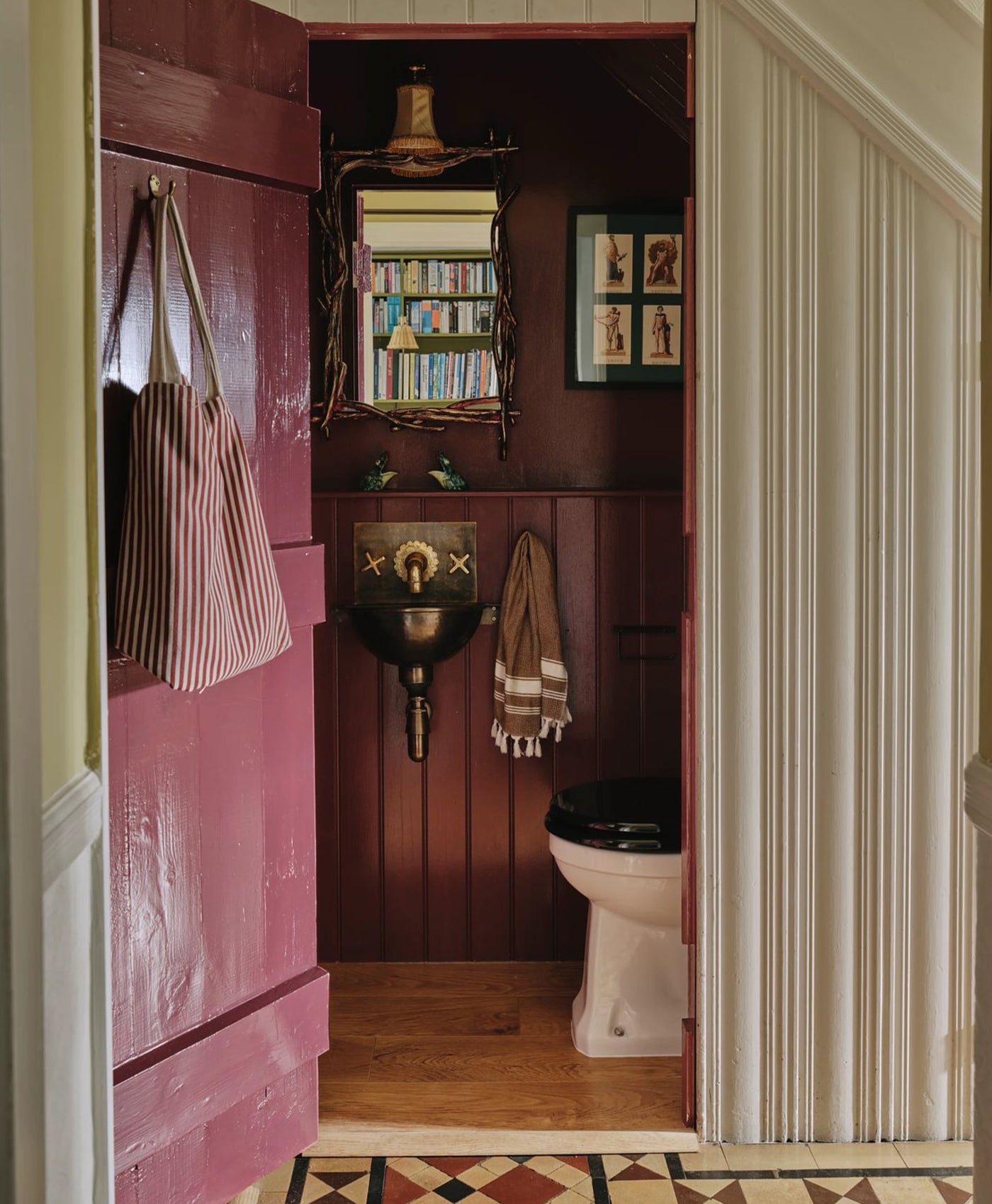 Small bathroom with burgundy wall, toilet, and mirror.