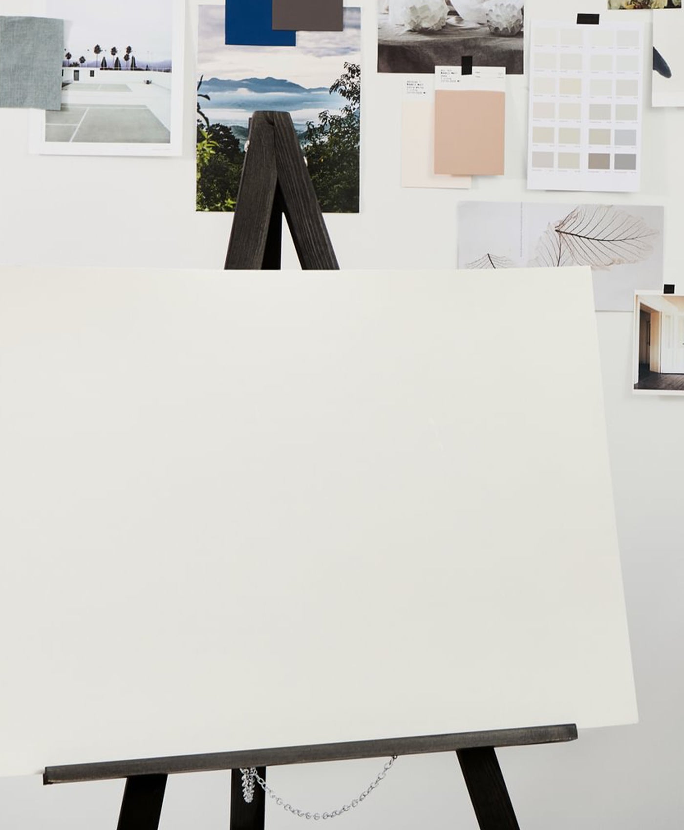 Easel with a blank canvas against a wall with color swatches and images