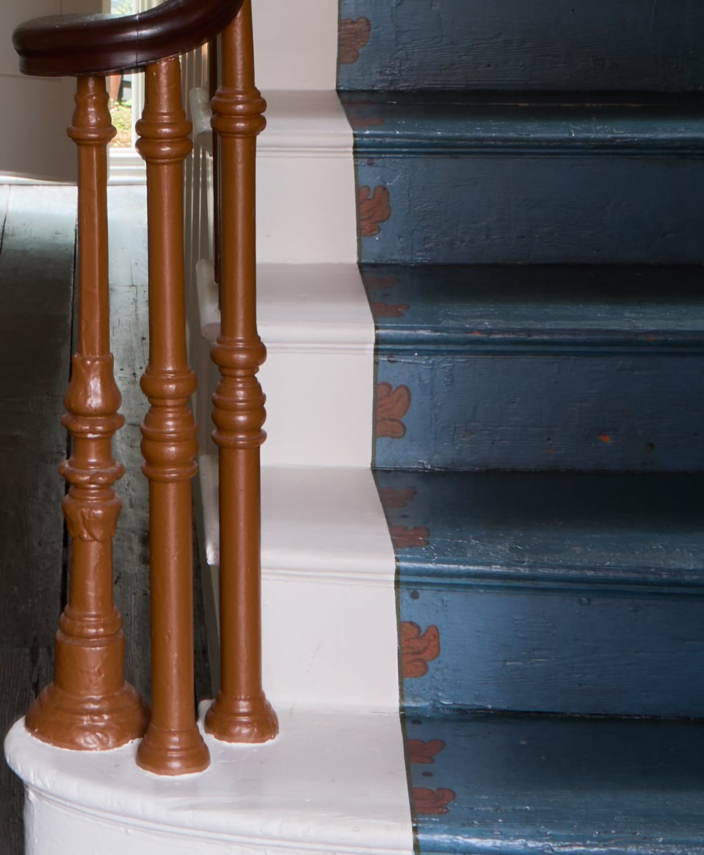 Staircase with wooden balusters painted in terracotta brown coloured paint and white and blue steps
