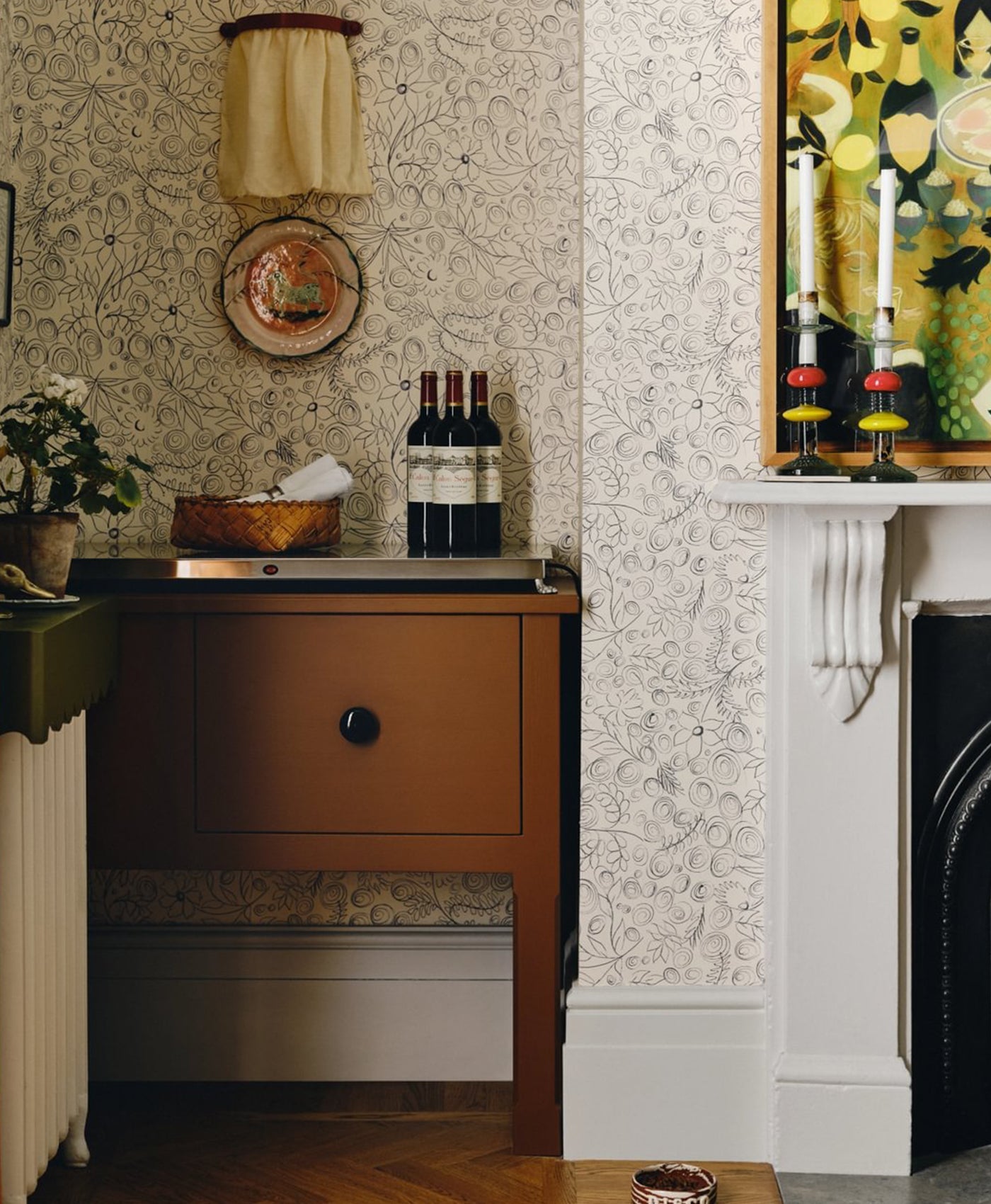 Vintage wooden cabinet, painted in toffee brown coloured paint with floral wallpaper, and decorative items.
