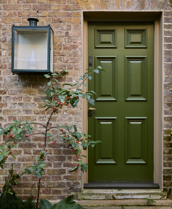 Olive green exterior door of brick house