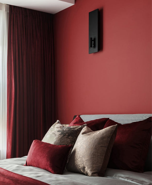 Bedroom with deep red walls, dark red curtains, and patterned pillows.