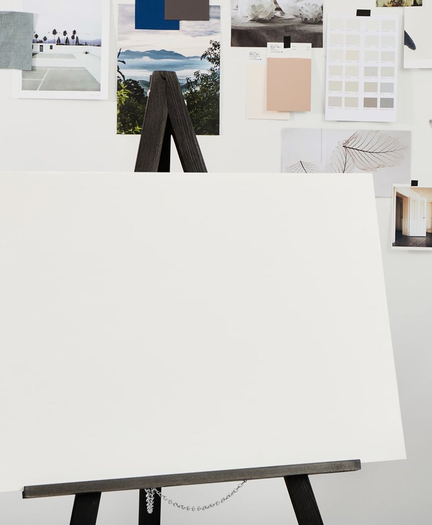 White easel with a black stand against a white wall with various color swatches and images displayed.