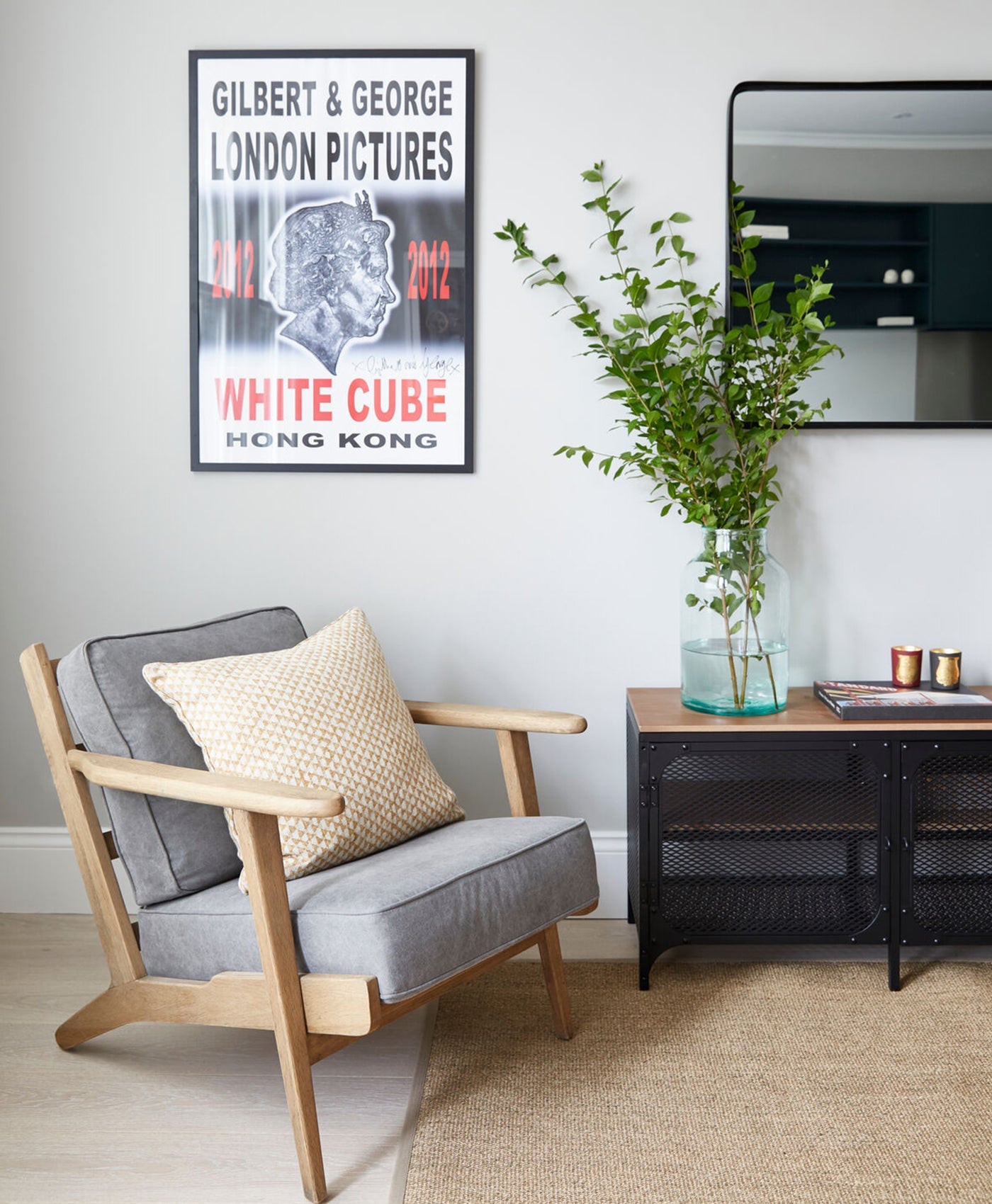 Modern pale grey living room with a chair, plant, and artwork on the wall.