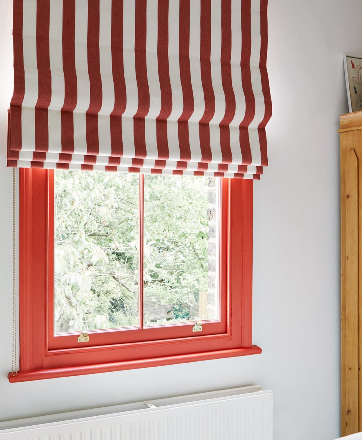 Window with red and white striped curtain and red window frame.