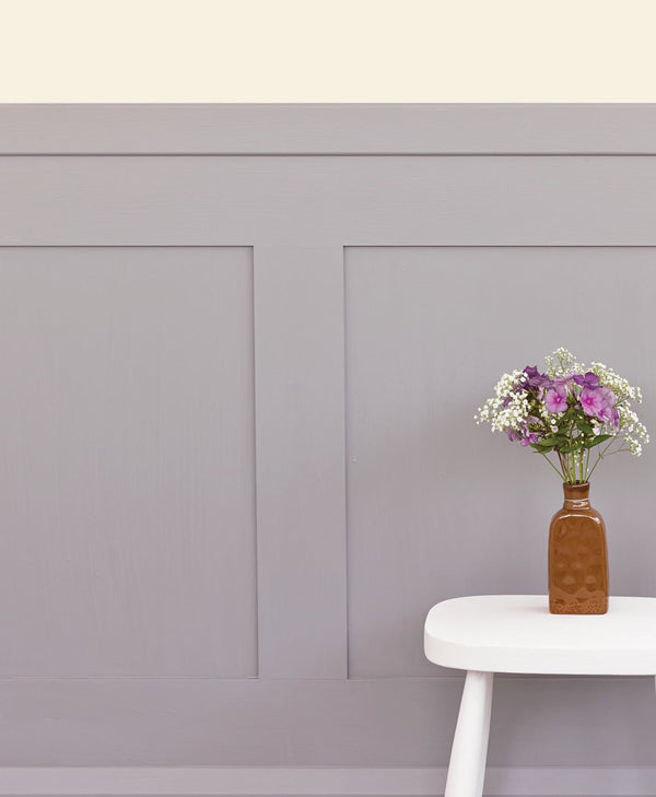 Vase with flowers on a white stool against a lilac grey wall