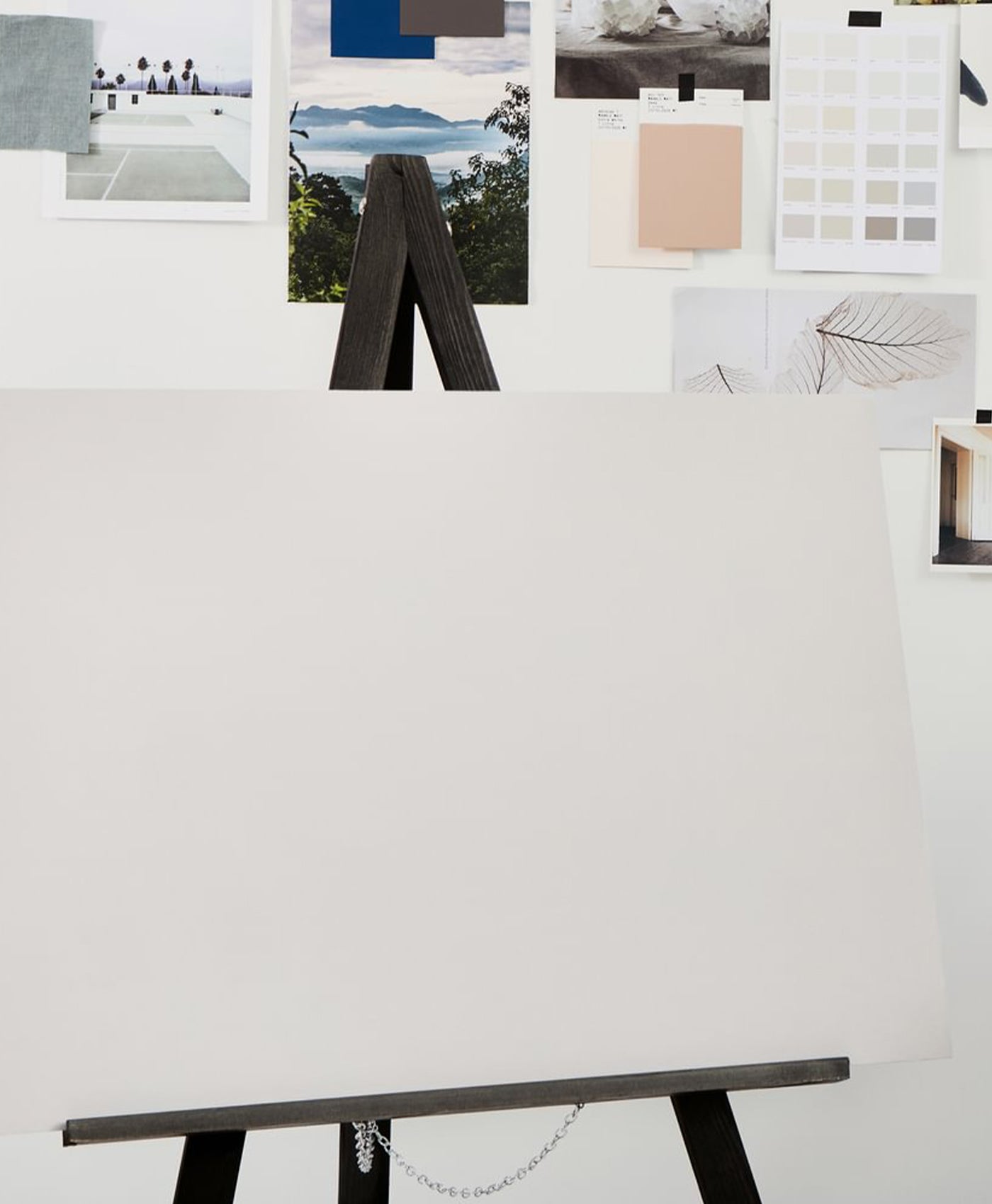 White canvas on a black easel with a white wall in the background