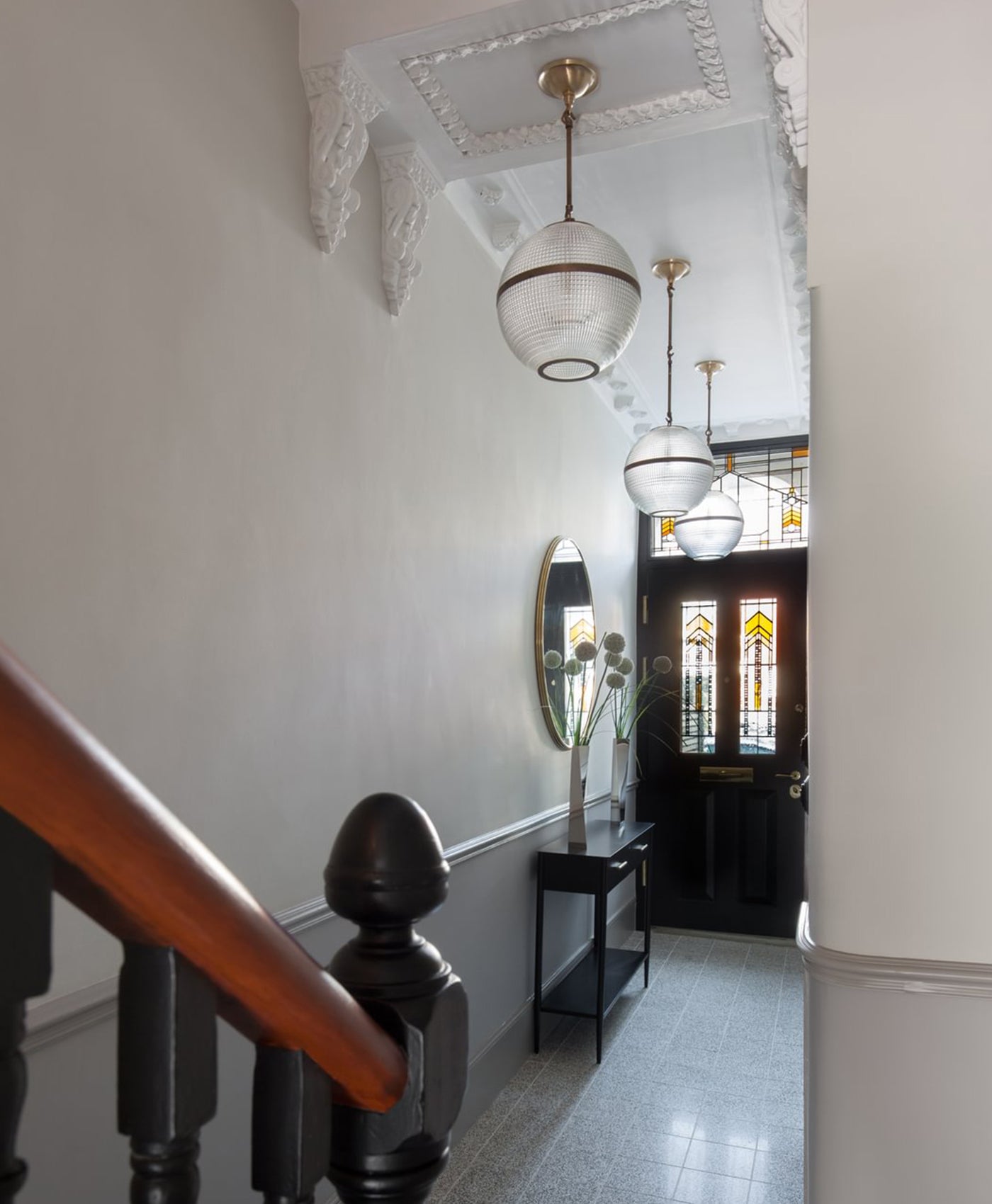 Staircase with wooden handrail and decorative ceiling lights in a white painted hallway home interior.