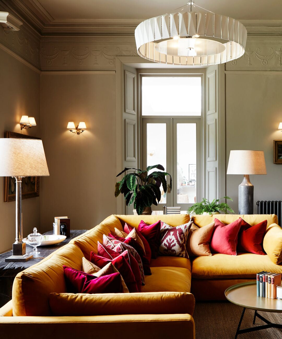 Light green grey living room with yellow sofa, pink pillows, and decorative items.