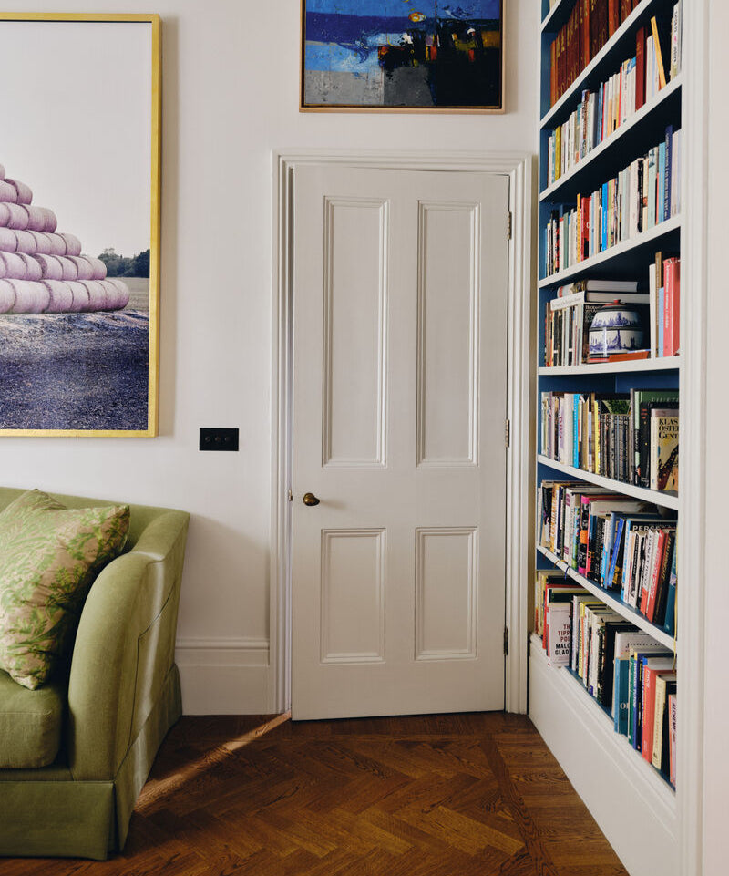 Beata Heuman's Living room with a green sofa, bookshelf, and framed pictures on the wall.