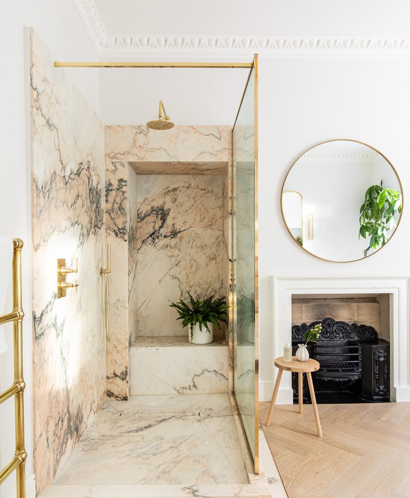 Soft off-white modern bathroom with marble walls, gold fixtures, and a round mirror.