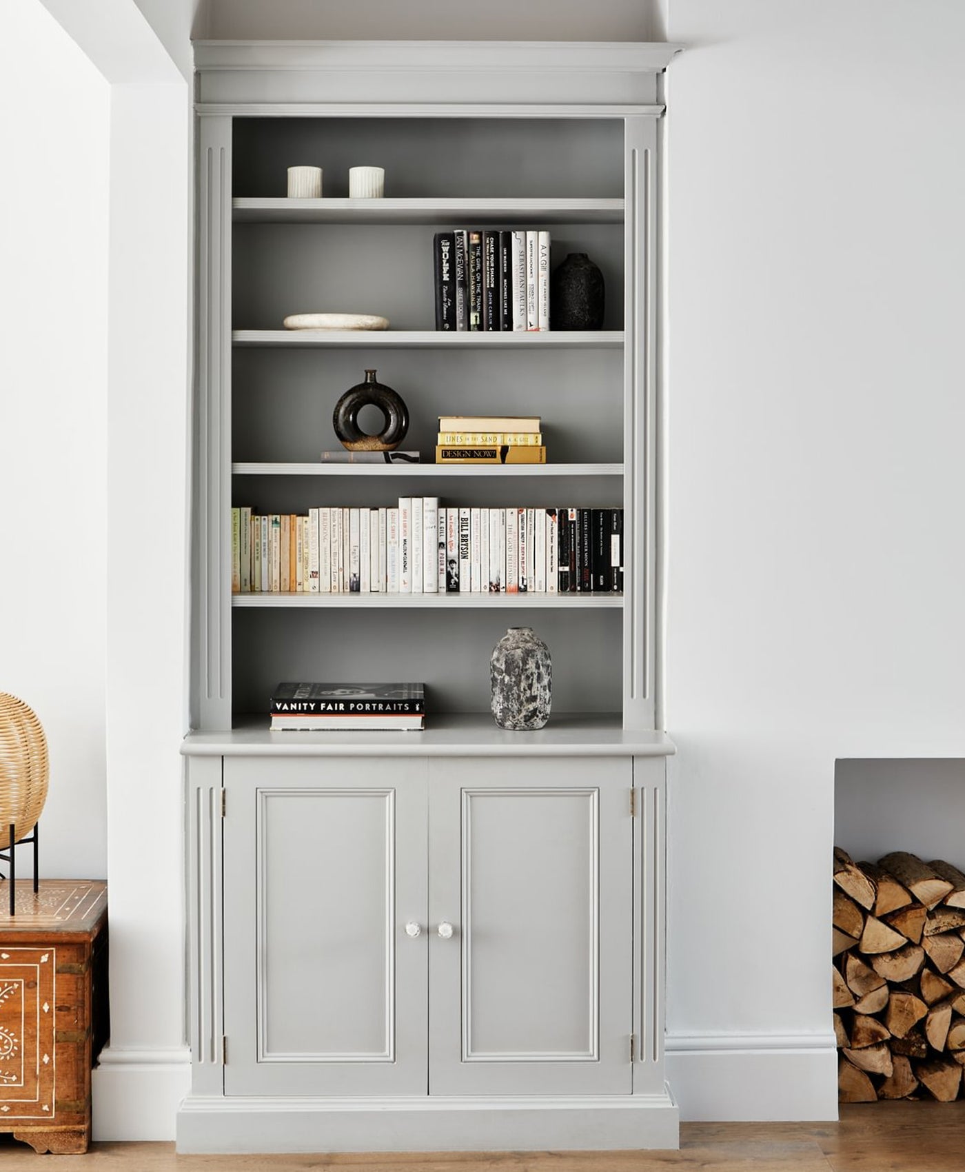 Grey bookshelf with decorative items against a white wall.