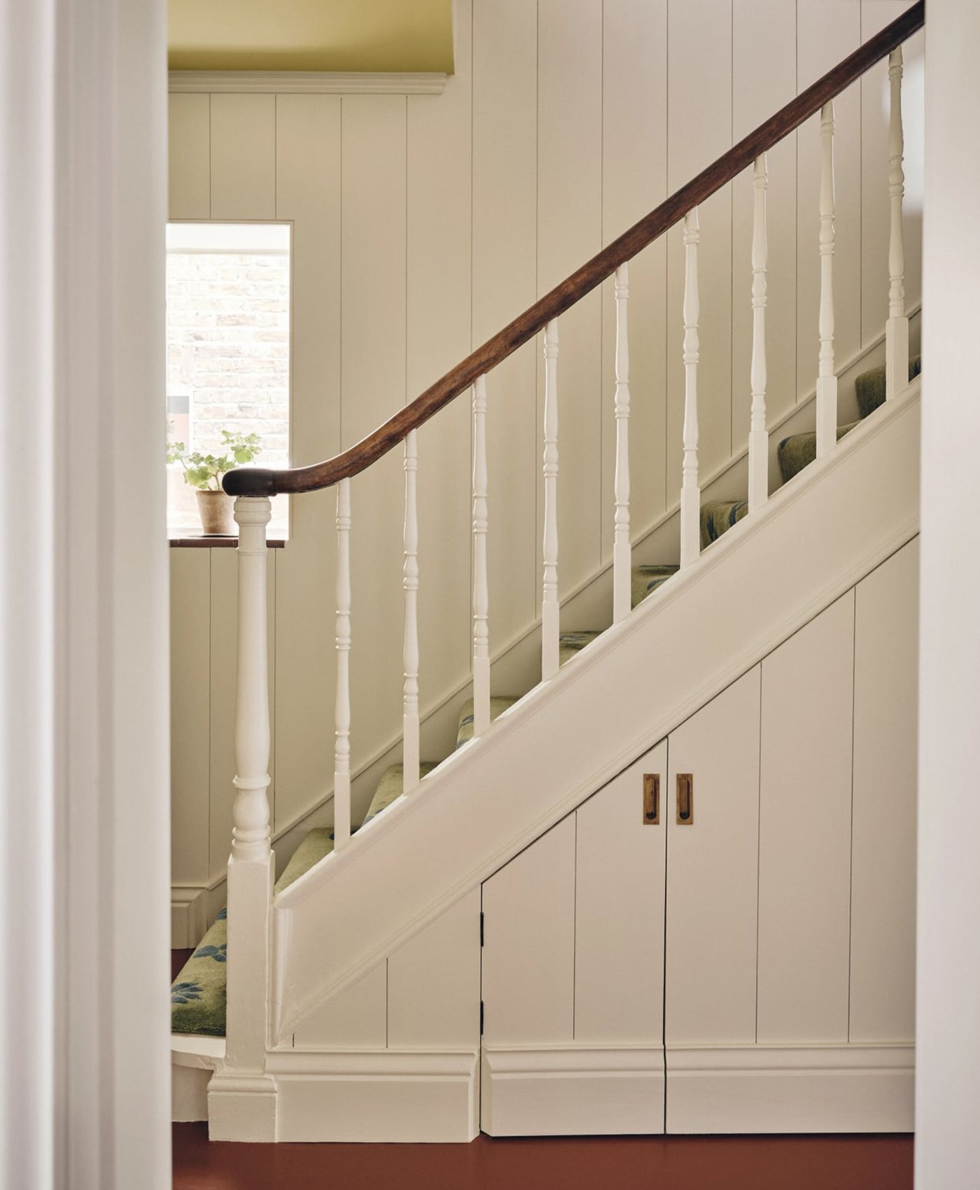 Staircase painted in warm white and wooden handrail in a home interior.
