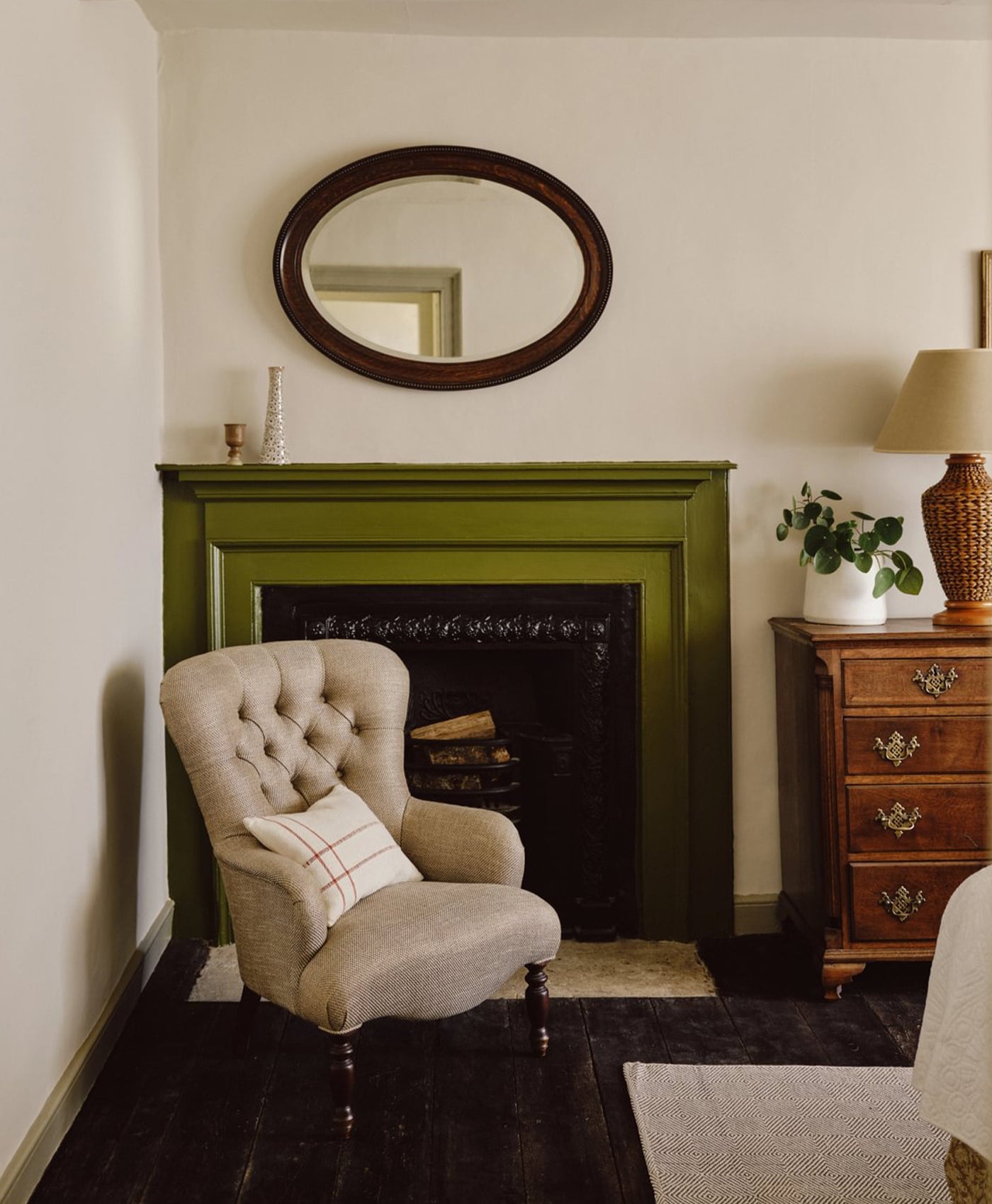 Cosy living room with a olive green fireplace, beige armchair, and wooden side table.