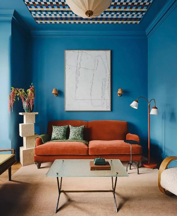 Vivid blue living room with orange sofa, and decorative elements.