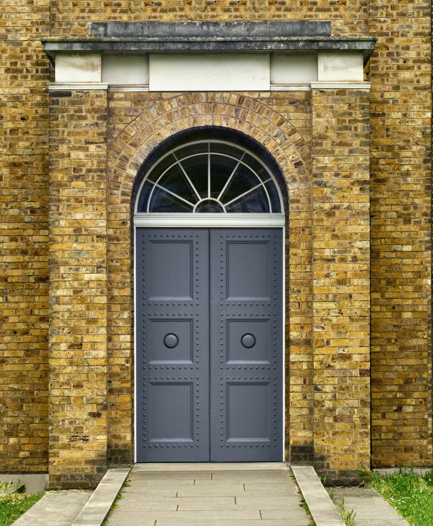 Grey door with decorative elements on a brick wall