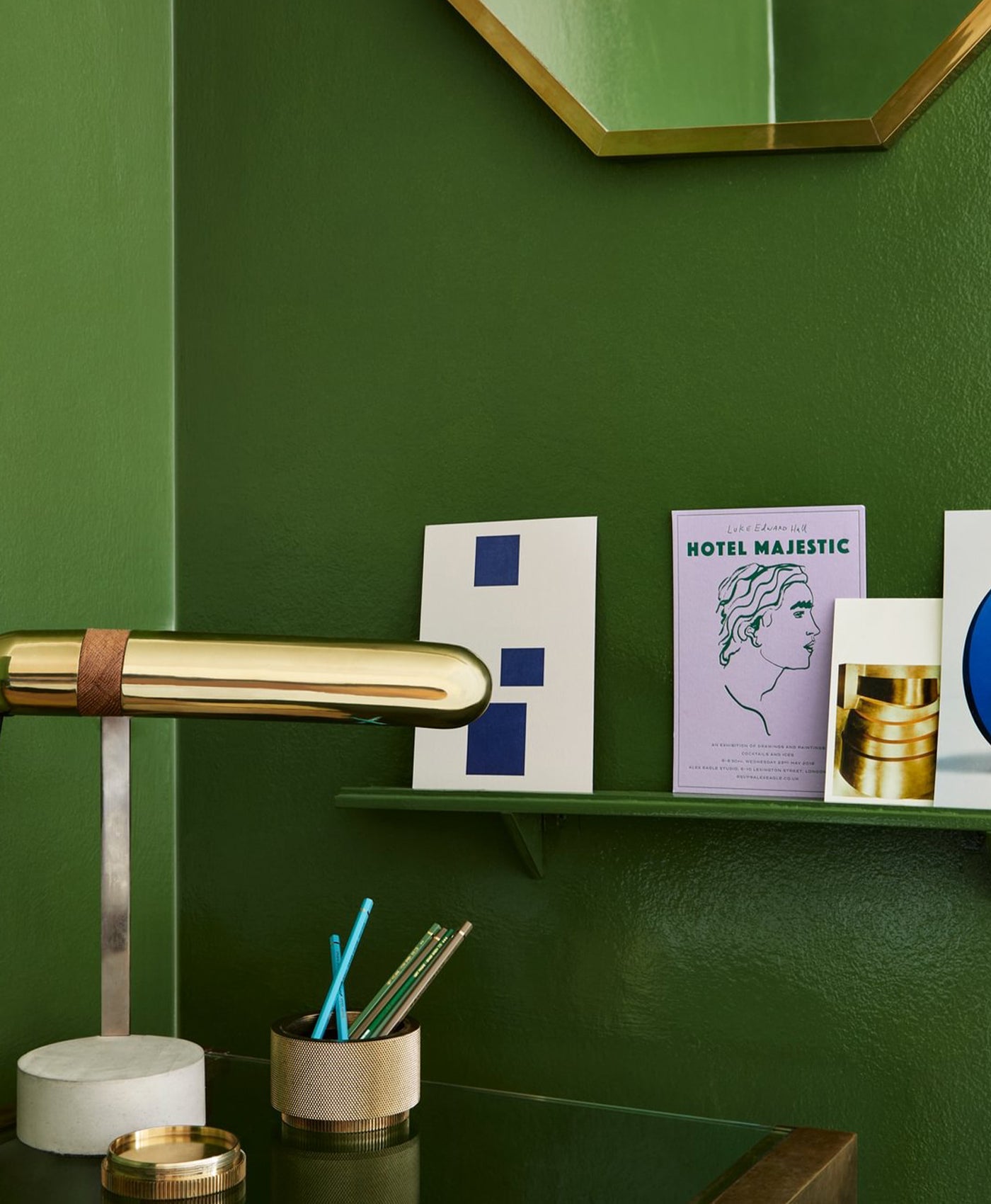 Decorative shelf with books and a lamp against a green wall