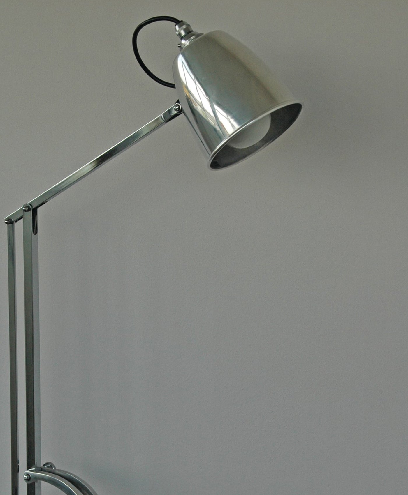 Silver floor lamp against a plain soft grey background wall colour