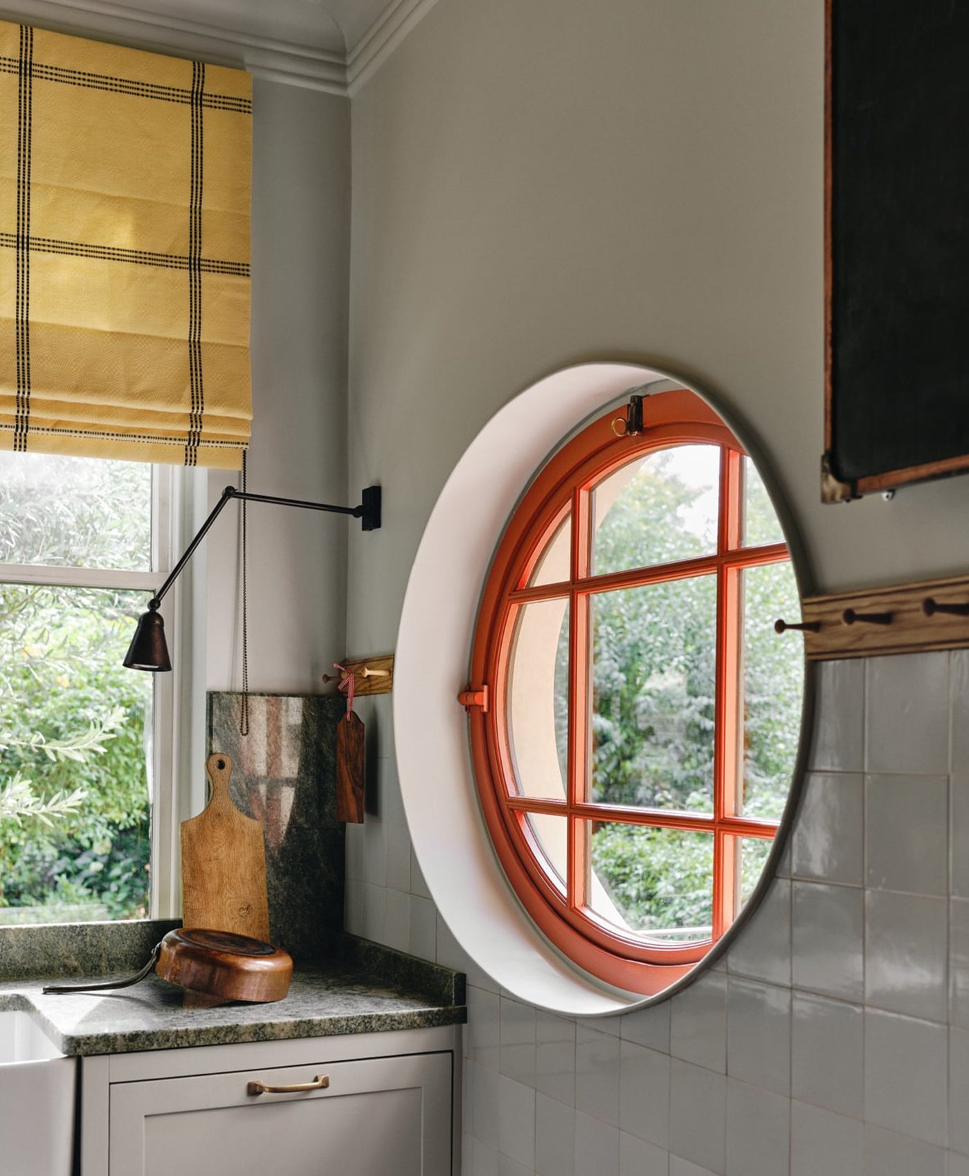 Round window with red wooden frame in a kitchen setting