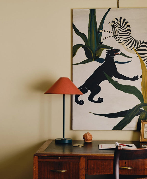 Decorative wall art with a panther and zebra on a buttermilk wall above a wooden desk.