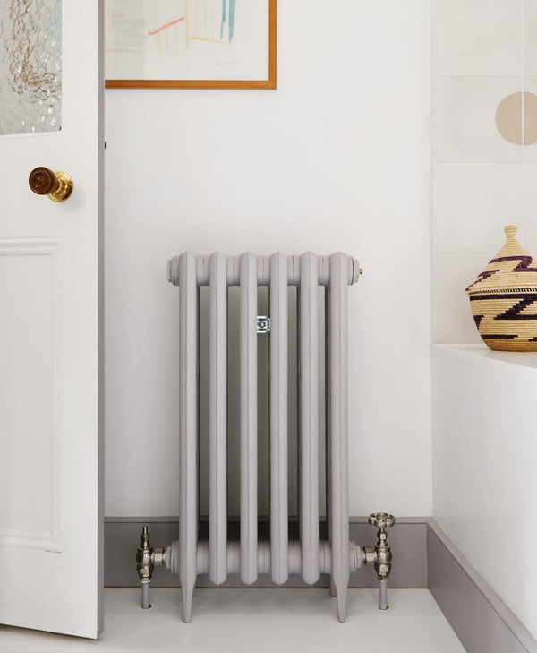 Mid grey radiator in a room with a white wall and decorative elements.