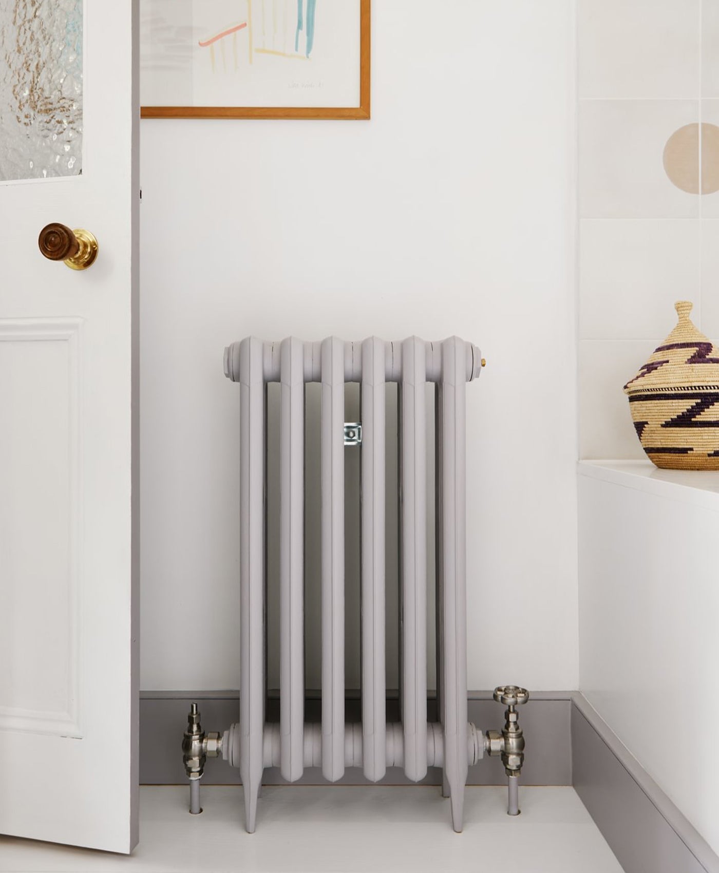 Mid grey radiator in a room with a white wall and decorative elements.