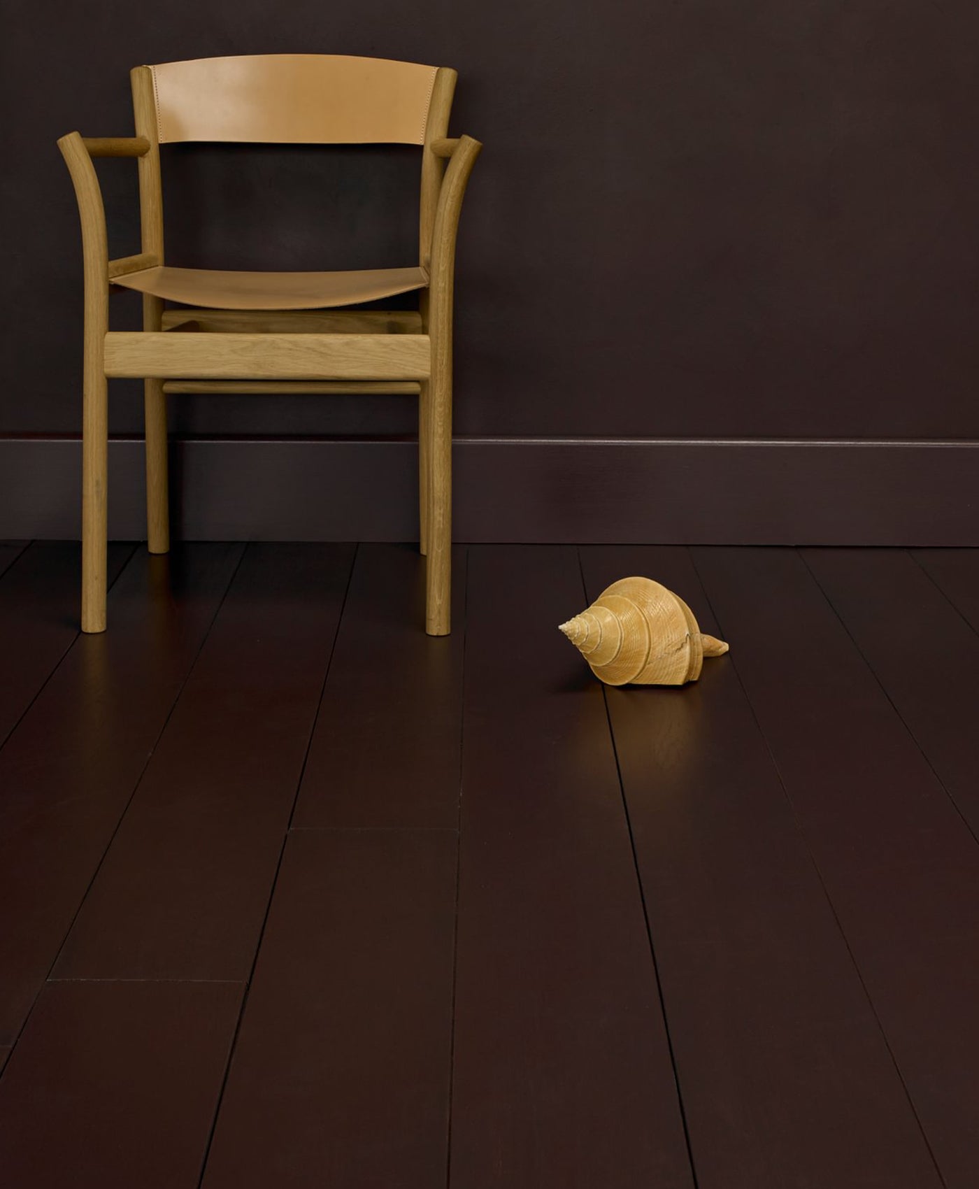Wooden chair and plush toy on a dark red wooden floor against a dark plum painted wall