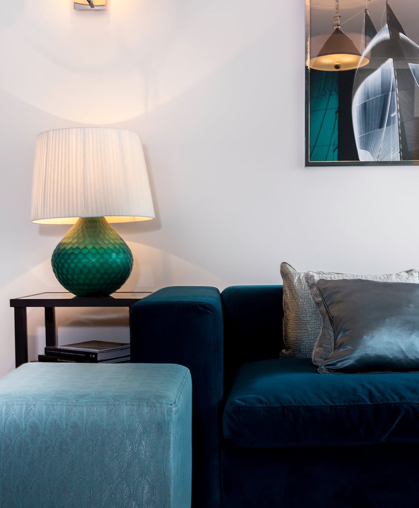 Modern neutral living room with teal sofa, lamp, and abstract art on white wall